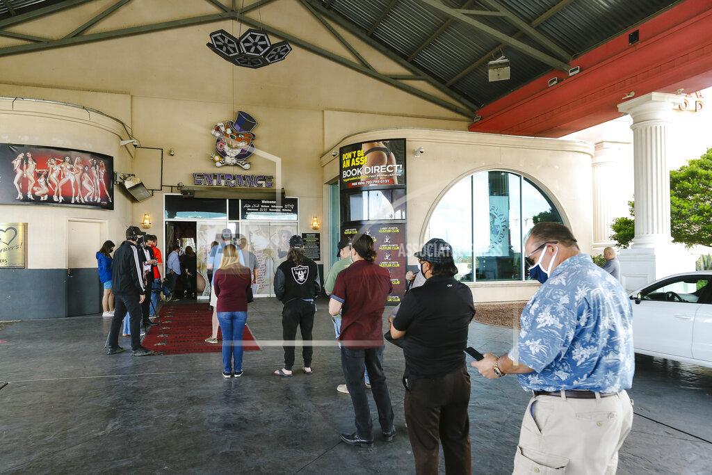 Wade Vandervort FILE - In this May 21, 2021, file photo, people wait in line during a pop-up COVID-19 vaccine event at Larry Flynt's Hustler Club in Las Vegas. It's one of several methods health officials are employing here and across the country to bring vaccines directly to people to counter waning demand. In tiny towns, ballparks, strip clubs, and marijuana dispensaries, officials are setting up shop and offering incentives to entice people who so far have not gotten shots. (Wade Vandervort/Las Vegas Sun via AP, File)