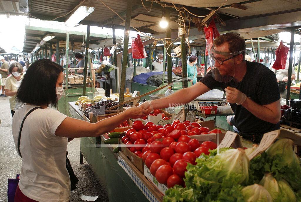 Boris Grdanoski A woman buys vegetables in a market in Skopje, North Macedonia on Thursday, July 16, 2020. The pro-Western SDSM party in North Macedonia is poised to try to form a coalition government following a narrow election victory. (AP Photo/Boris Grdanoski)