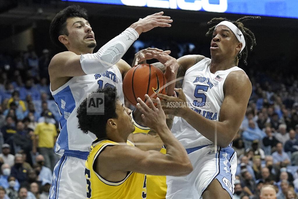 Gerry Broome North Carolina forward Dawson Garcia, left, and forward Armando Bacot (5) struggle for possession of the ball with Michigan guard Eli Brooks during the second half of an NCAA college basketball game in Chapel Hill, N.C., Wednesday, Dec. 1, 2021. (AP Photo/Gerry Broome)