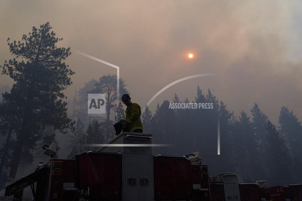 Jae C. Hong Firefighter Walter Villalobos from Cosumnes Fire Department stands on top of a fire truck as the sun is visible through smoke generated by the Caldor Fire near South Lake Tahoe, Calif., Friday, Sept. 3, 2021. Fire crews took advantage of decreasing winds to battle a California wildfire near popular Lake Tahoe and were even able to allow some people back to their homes but dry weather and a weekend warming trend meant the battle was far from over. (AP Photo/Jae C. Hong)
