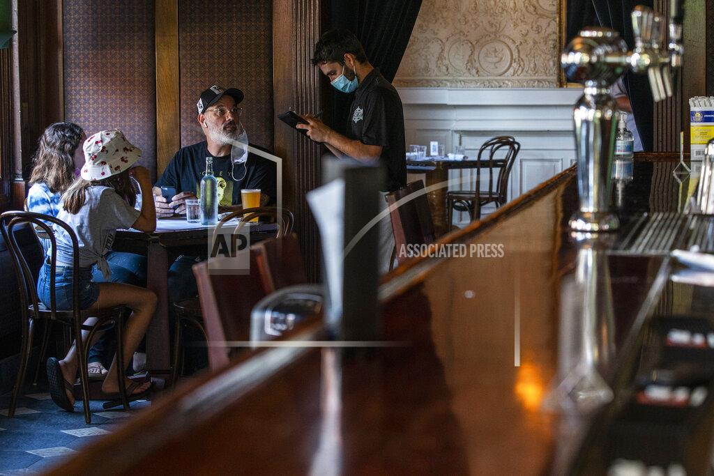 A waiter in a face mask takes the order of customers inside a local restaurant during lunch during the coronavirus pandemic on Friday, Sept. 4, 2020, in Hoboken, N.J. (AP Photo/Eduardo Munoz Alvarez)