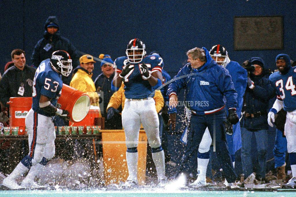FILE - In this Jan. 11, 1987, file photo, New York Giants George Martin (75) watches as teammate Harry Carson empties the water bucket on coach Bill Parcells during the last minute of their 17-0 win over the Washington Redskins in the NFC championship in East Rutherford, N.J. Teams are never supposed to choose to kick off after winning the coin toss because it means they won't get the ball to start either half. But games rarely have wind gusts of 25 mph and beyond. That was the case when the Giants beat the Redskins 17-0 for the 1986 NFC title. (AP Photo/Elise Amendola, File)
