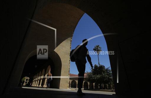 FILE - In this April 9, 2019, file photo, pedestrians walk on the campus at Stanford University in Stanford, Calif. Thousands of public servants who were rejected from a student loan forgiveness program will get their cases reviewed by the Education Department as part of a new settlement in a lawsuit brought by one of the nation's largest teachers unions. (AP Photo/Jeff Chiu, File)