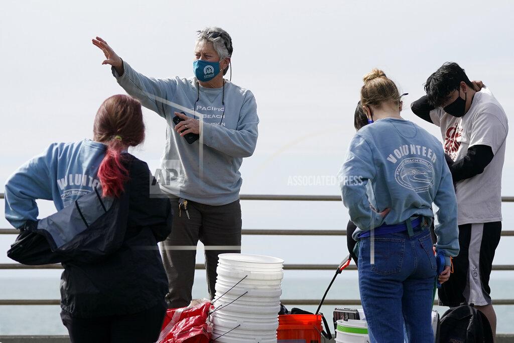 Jeff Chiu Lynn Adams, president of the Pacifica Beach Coalition, center, gives directions to volunteers before they clean areas near Sharp Park Beach in Pacifica, Calif., Wednesday, March 17, 2021. Disposable masks, gloves and other personal protective equipment have safeguarded untold lives during the pandemic. They’re also creating a worldwide environmental problem, littering streets and sending an influx of harmful plastic into landfills and oceans. (AP Photo/Jeff Chiu)