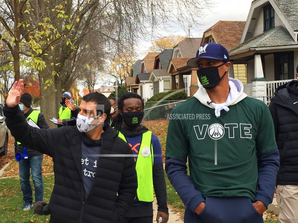 FILE - In this Oct. 24, 2020 file photo, Milwaukee Bucks senior vice president Alex Lasry, left, and then-Bucks guard George Hill walk through a Milwaukee neighborhood during a voter canvassing effort. Lasry received the COVID-19 vaccine this week at a senior living center in Milwaukee. Alex Lasry told the Milwaukee Journal Sentinel in a story published Friday, Jan. 29, 2021, that he "just got lucky" and didn't receive any favoritism. (AP Photo/Steve Megargee File)