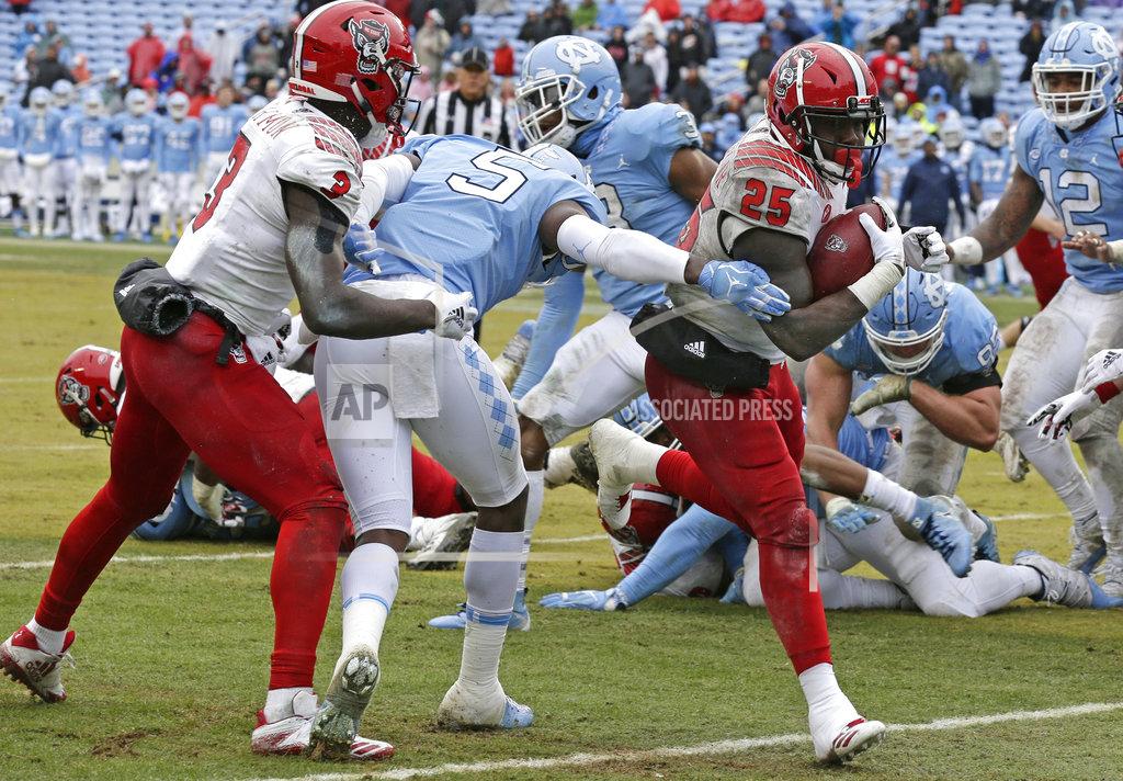 Gerry Broome North Carolina State's Reggie Gallaspy II (25) scores a touchdown as Kelvin Harmon (3) blocks North Carolina's Patrice Rene (5) during the second half of an NCAA college football game in Chapel Hill, N.C., Saturday, Nov. 24, 2018. North Carolina State won 43-28 in overtime. (AP Photo/Gerry Broome)