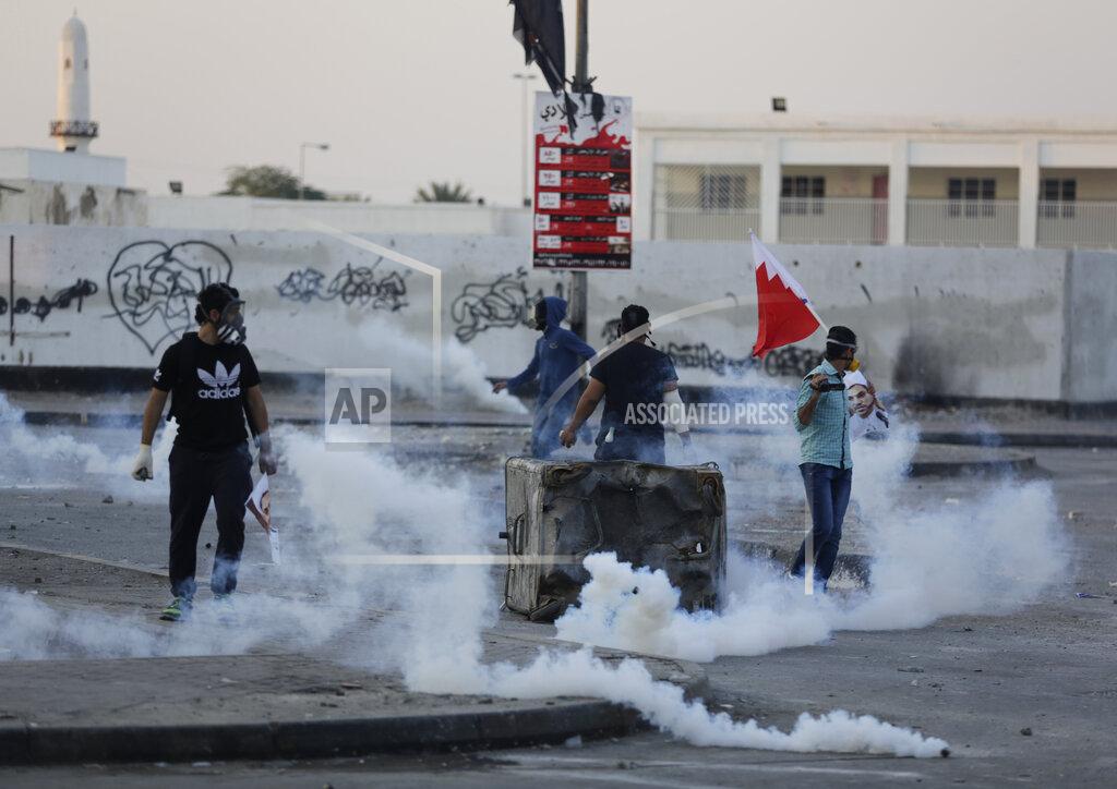 Hasan Jamali File - Int his Friday, Jan. 2, 2015 file photo, Bahraini anti-government protesters, one holding a national flag, clash with riot police firing tear gas in Bilad Al Qadeem, a suburb of Manama, Bahrain. A decade ago, against all odds, a popular uprising convulsed the monarchy of Bahrain as a wave of revolutionary protests swept across the Middle East. But after a brutal crackdown and years of escalating repression, activists say the small kingdom is less free now than even before the Arab Spring, as authorities crush hopes for political reform. (AP Photo/Hasan Jamali, File)