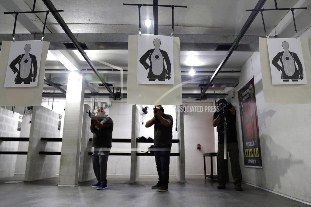 Eraldo Peres Shooters take their position during a practice session at the Valparaiso Shooting Club on the outskirts of Brasilia, Brazil, Saturday, March 6, 2021. President Jair Bolsonaro and his supporters believe that looser gun laws are necessary to fight crime and improve security in the nation with more homicides than any other. (AP Photo/Eraldo Peres)