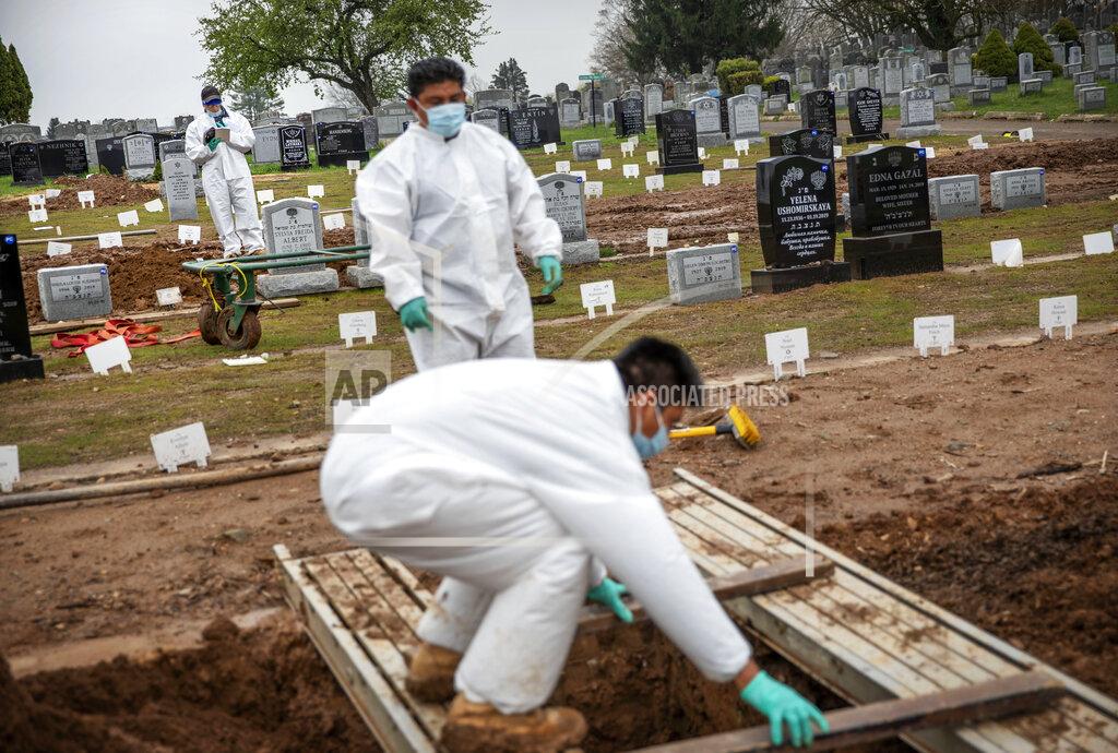 David Goldman Rabbi Shmuel Plafker, rear, finishes a prayer during the burial service for David Tokar as gravediggers prepare a plot for the next burial at Mount Richmond Cemetery in the Staten Island borough of New York, Wednesday April 8, 2020. When Plafker arrives at the cemetery, it's buzzing: Vans pulling in with bodies aboard, mounds of dirt piling up as graves are dug open, a line of white signs pressed into the ground marking plots that are newly occupied. Some of the few signs of life in this anguished city are coming from those tending to the dead. (AP Photo/David Goldman)