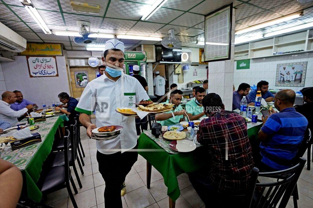 Kamran Jebreili A waiter with new Adidas Ravi signed uniform, carries food portions at Ravi restaurant in Satwa district of Dubai, United Arab Emirates, Wednesday, June 22, 2022. Adidas has teamed up with Dubai nostalgic family-owned Pakistani restaurant to release the Superstar Ravi sneaker. (AP Photo/Kamran Jebreili)