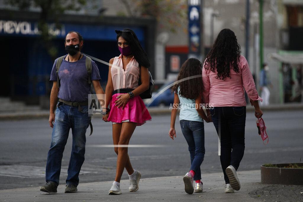 Rebecca Blackwell Sex worker Geraldine, 30, holds hands with her partner Miguel as she arrives outside the Revolution subway station to wait for clients, in Mexico City, Sunday, March 14, 2021. Miguel, who has been told to stay home from his job at a call center since his diabetes puts him at high risk for coronavirus complications, now spends his days accompanying Geraldine to work, exchanging jokes and the occasional kiss as he sits nearby, giving her snacks during the long hours of waiting, and keeping an eye on clients to help her stay safe in an area with high levels of crime and drug use. (AP Photo/Rebecca Blackwell)