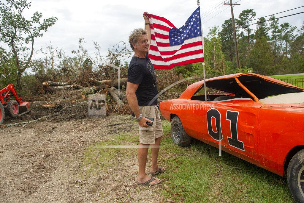 Chris Granger Actor John Schneider, who starred in the television show "The Dukes of Hazzard," places an American flag on his "General Lee" car on Monday, Sept. 6, 2021, that was destroyed by Hurricane Ida. The car was made famous during the show which aired in the early eighties. (Chris Granger/The Times-Picayune/The New Orleans Advocate via AP)