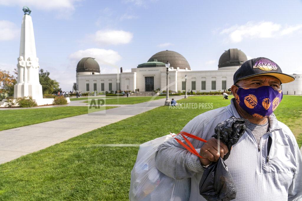 Damian Dovarganes Jose Cartamo, 64, originally from El Salvador, wears a face mask as he collects recyclables at the Griffith Observatory in Los Angeles, Monday, May 17, 2021. Cartamo plans to make an appointment to be vaccinated. California is keeping its rules for wearing face masks in place until the state more broadly lifts its pandemic restrictions on June 15. (AP Photo/Damian Dovarganes)