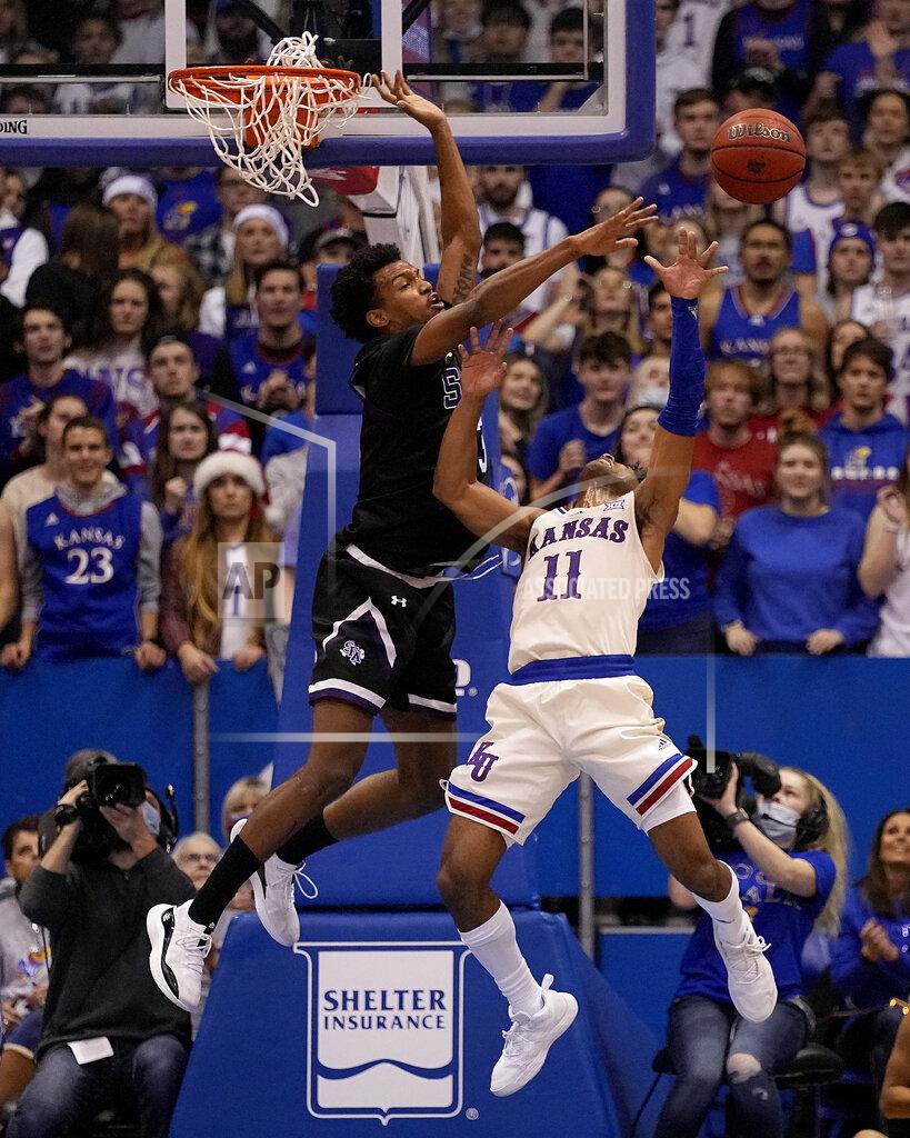 Charlie Riedel Stephen F. Austin's Calvin Solomon, left, blocks a shot by Kansas' Remy Martin (11) during the second half of an NCAA college basketball game Saturday, Dec. 18, 2021, in Lawrence, Kan. (AP Photo/Charlie Riedel)