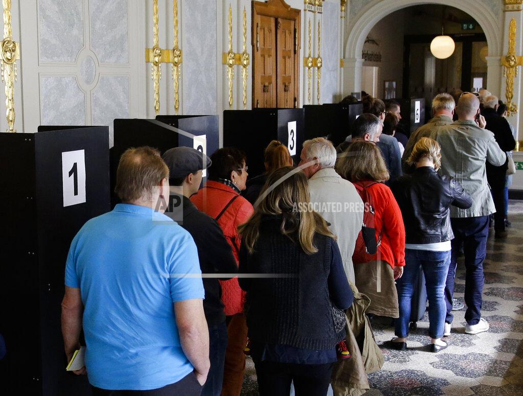 Markus Schreiber FILE- In this Tuesday, Sept. 19, 2017 file photo, people line up to cast their votes at a polling station for the absentee vote in Berlin, Germany. German voters elect a new parliament on Sunday, Sept. 26, 2021, a vote that will determine who succeeds Chancellor Angela Merkel after her 16 years in power. (AP Photo/Markus Schreiber, File)