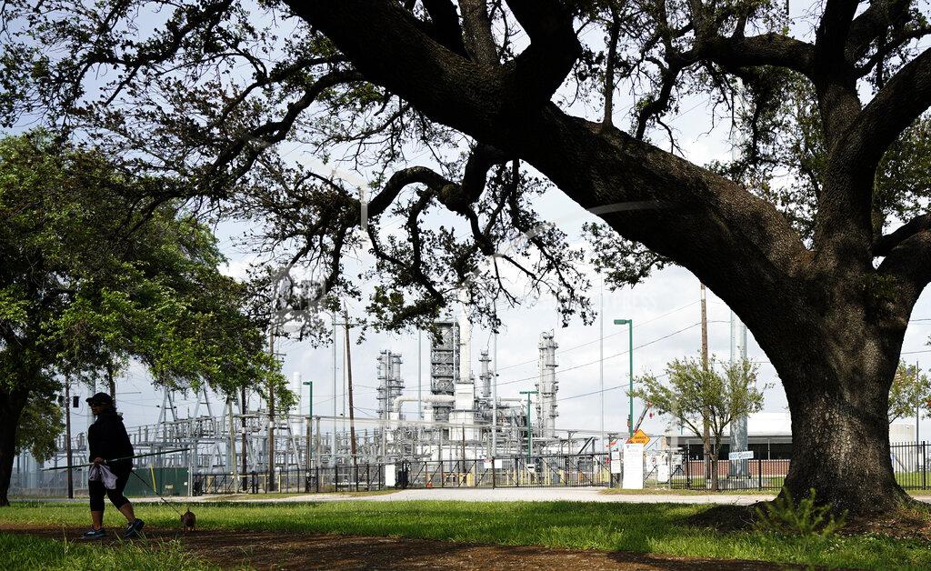 David J. Phillip A woman walks her dog in Hartman Park next to the Valero Houston Refinery Monday, March 23, 2020, in Houston. (AP Photo/David J. Phillip)
