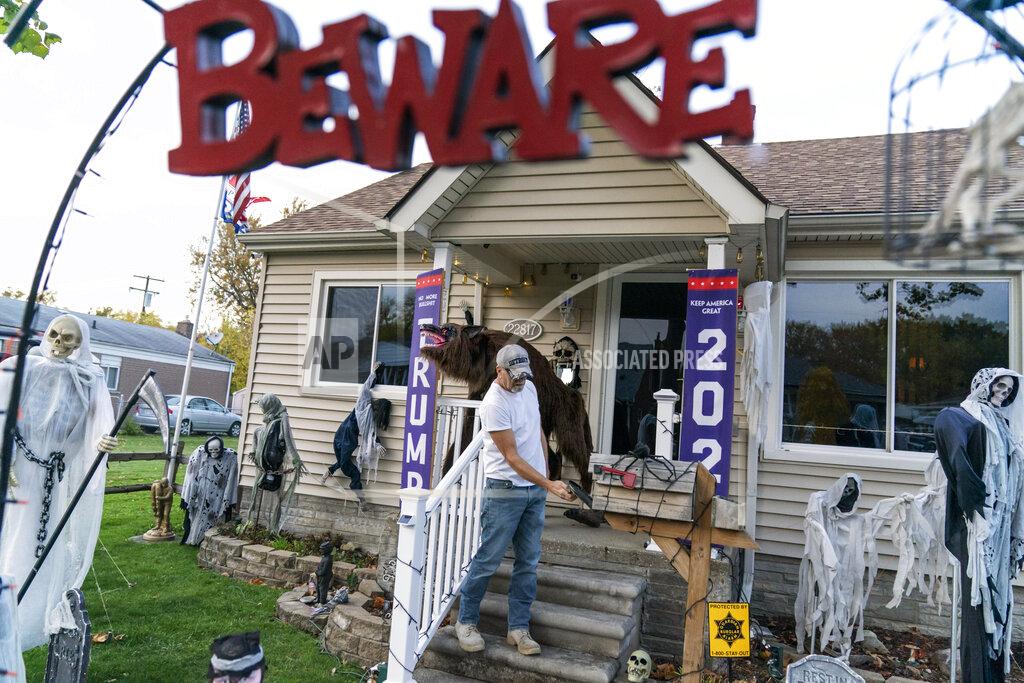 Trump supporter Terry Frandle checks his mailbox in his front yard decorated for Halloween and a Trump reelection campaign in Saint Clair Shores, Mich., Wednesday, Oct. 28, 2020. In Macomb County, Frandle hung Trump banners outside his house and noticed that neighbors who used to stop to chat crossed to the other side of the street, not even offering a "hello." Some drivers wave, some flip the bird. He doesn't blame Trump for the discord, he blames Democrats and the media for failing to give Trump a fair shake, he said. He plans to vote in person on Election Day. "I just don't trust anything anymore," he said, except for what he hears directly from Trump. (AP Photo/David Goldman)