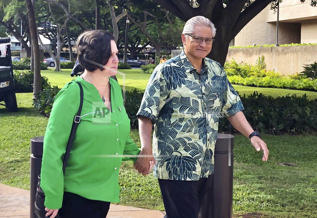 FILE - In this March 12, 2019, file photo, retired Honolulu police chief Louis Kealoha and his wife, former deputy city prosecutor Katherine Kealoha, hold hands while walking to U.S. district court in Honolulu. A once-respected, now-estranged power couple are scheduled to be sentenced Monday, Nov. 30, 2020, in Hawaii's biggest corruption case. A jury convicted Katherine and Louis Kealoha of conspiracy in a plot to frame her uncle to keep him from revealing fraud that financed their fancy lives. (AP Photo/Jennifer Sinco Kelleher, File)