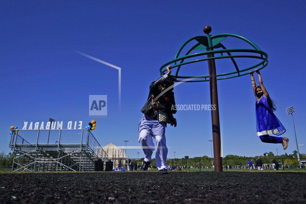 Seth Wenig Saif Chaudhry plays with his daughter Ariana Chaudhry, 8, on playground near the site of an outdoor celebration of Eid al-Fitr in Overpeck County Park in Ridgefield Park, N.J., Thursday, May 13, 2021. Millions of Muslims across the world are marking a muted and gloomy holiday of Eid al-Fitr, the end of the fasting month of Ramadan - a usually joyous three-day celebration that has been significantly toned down as coronavirus cases soar. (AP Photo/Seth Wenig)