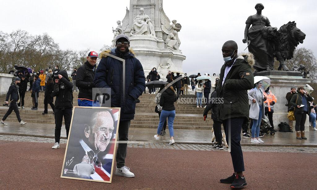 Alberto Pezzali A man stands with an artwork depicting Britain's Prince Philip outside Buckingham Palace in London, a day after the death of Britain's Prince Philip, Saturday, April 10, 2021. Britain's Prince Philip, the irascible and tough-minded husband of Queen Elizabeth II who spent more than seven decades supporting his wife in a role that mostly defined his life, died on Friday. (AP Photo/Alberto Pezzali)
