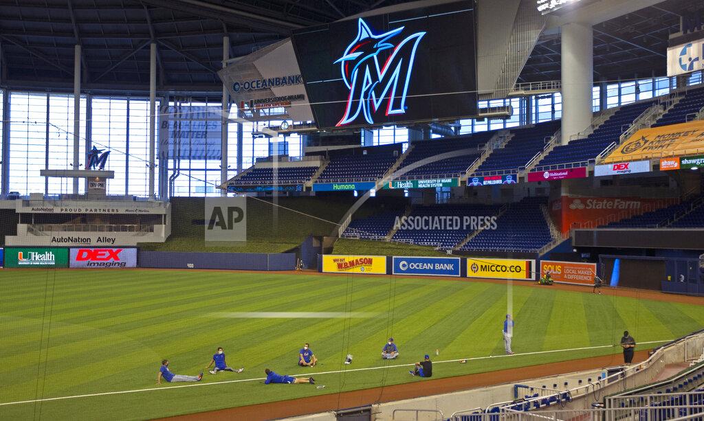 David Santiago New York Mets players sit on the field before a baseball game against the Miami Marlins, Thursday, Aug. 20, 2020, in Miami. Major League Baseball says the Mets have received two positive tests for COVID-19 in their organization, prompting the postponement of two games. (David Santiago/Miami Herald via AP)