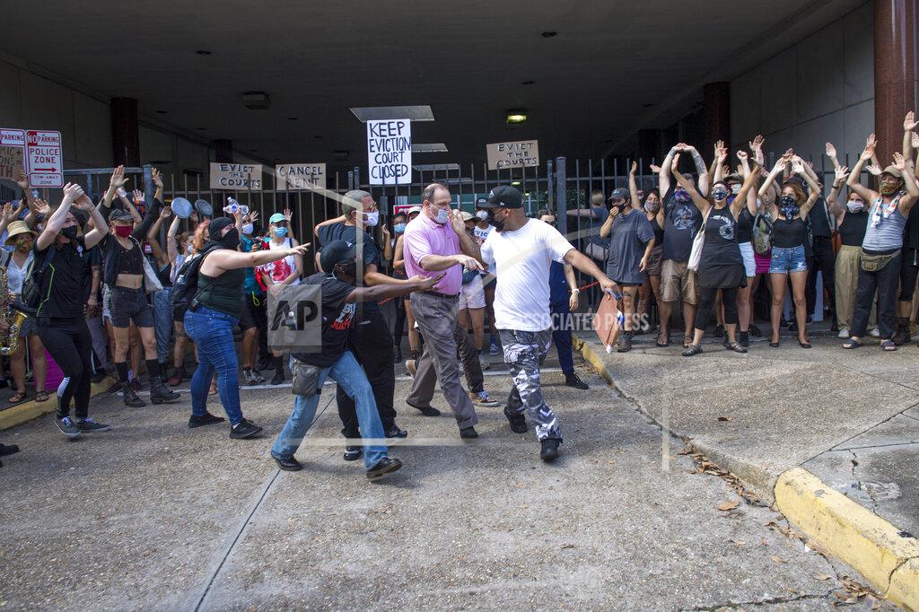Chris Granger A protester, right center, walks away with paperwork after grabbing it out of the hands of a man, center, who was trying to enter First City Court while the New Orleans Renters Rights Assembly protest was taking place outside First City Court near New Orleans City Hall on Thursday, July 30, 2020. Other protesters intervened and returned the paperwork to the man. (Chris Granger/The Advocate via AP)