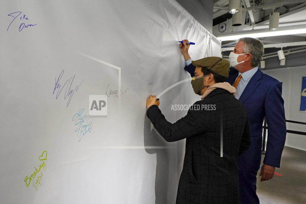 Richard Drew Actor Lin-Manuel Miranda, left, and New York Mayor Bill de Blasio, sign the autograph wall after they toured the grand opening of a Broadway COVID-19 vaccination site intended to jump-start the city's entertainment industry, in New York, Monday, April 12, 2021. (AP Photo/Richard Drew, Pool)