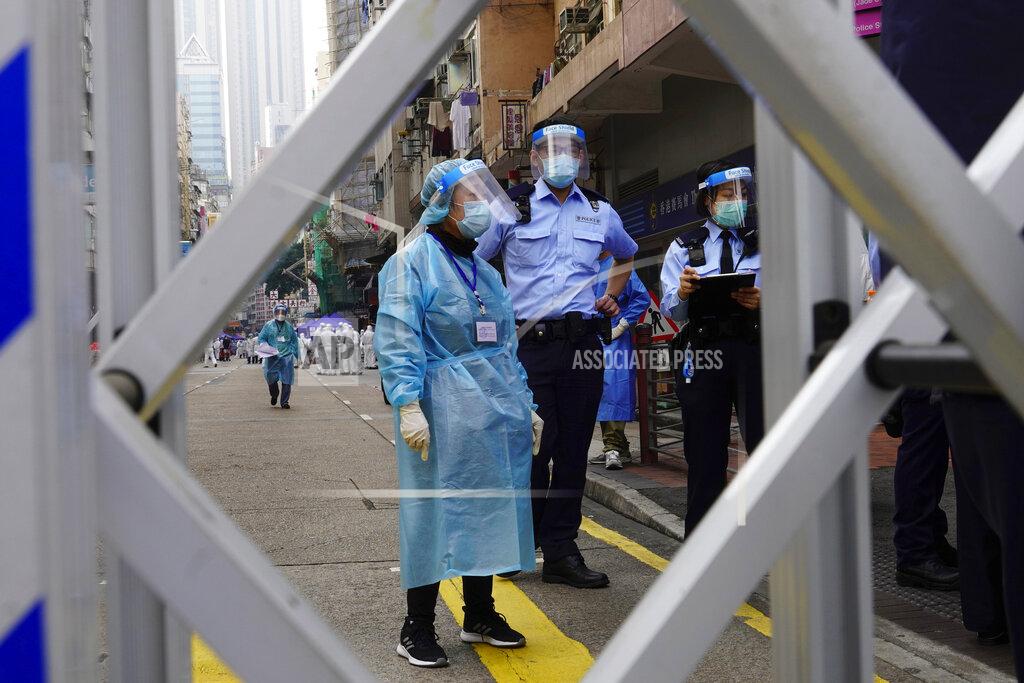 Vincent Yu Police officers and health officials stand guard at the Yau Ma Tei area, in Hong Kong, Saturday, Jan. 23, 2021. Thousands of Hong Kong residents were locked down Saturday in an unprecedented move to contain a worsening outbreak in the city, authorities said. (AP Photo/Vincent Yu)