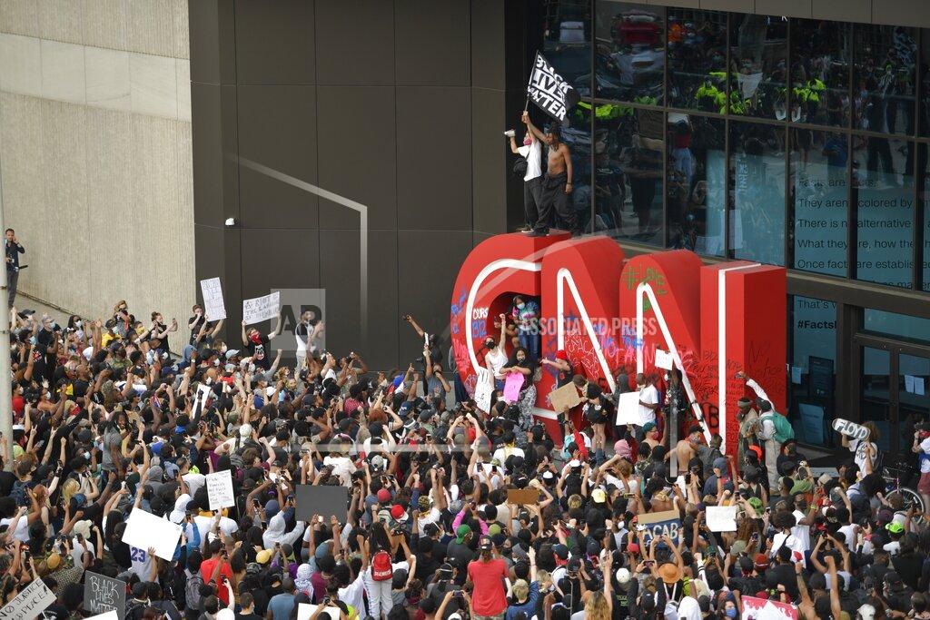 Mike Stewart EDS NOTE: OBSCENITY - Demonstrators paint on the CNN logo during a protest, Friday, May 29, 2020, in Atlanta, in response to the death of George Floyd in police custody on Memorial Day in Minneapolis. The protest started peacefully earlier in the day before demonstrators clashed with police. (AP Photo/Mike Stewart)