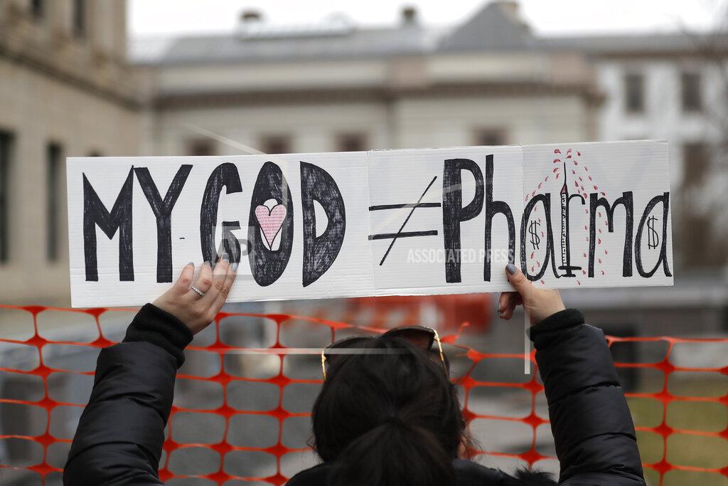 Seth Wenig FILE - In this Jan. 13, 2020, file photo, a woman holds a sign during a protest at the state house in Trenton, N.J. Religious objections, once used only sparingly around the country to get exempted from various required vaccines, are becoming a much more widely used loophole against the COVID-19 shot. (AP Photo/Seth Wenig, File)