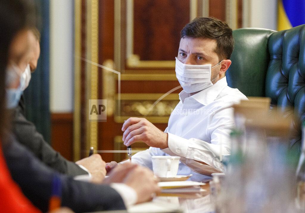 Uncredited FILE - In this photo taken on Wednesday April 22, 2020, Ukrainian President Volodymyr Zelenskiy in a face mask to protect against coronavirus, discusses the COVID-19 situation in the country with officials in his office in Kyiv, Ukraine. Zelenskiy has switched to a special work mode as his wife Olena was tested positive for the coronavirus, his office said. (Ukrainian Presidential Press Office via AP)