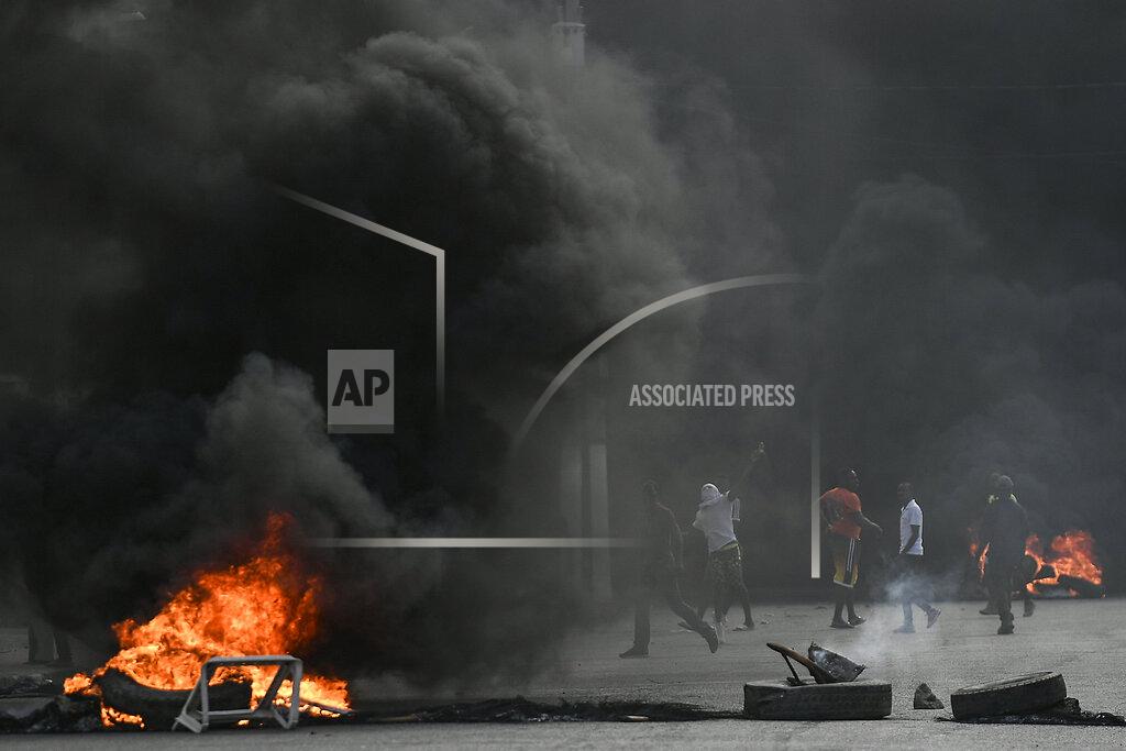 Matias Delacroix Protesters demanding justice for the assassinated President Jovenel Moise stand between burning barricades in Cap-Haitien, Haiti, Thursday, July 22, 2021. Demonstrations after a memorial service for Moise turned violent on Thursday afternoon with protesters shooting into the air, throwing rocks and overturning heavy concrete barricades next to the seashore as businesses closed and people took cover. (AP Photo/Matias Delacroix)