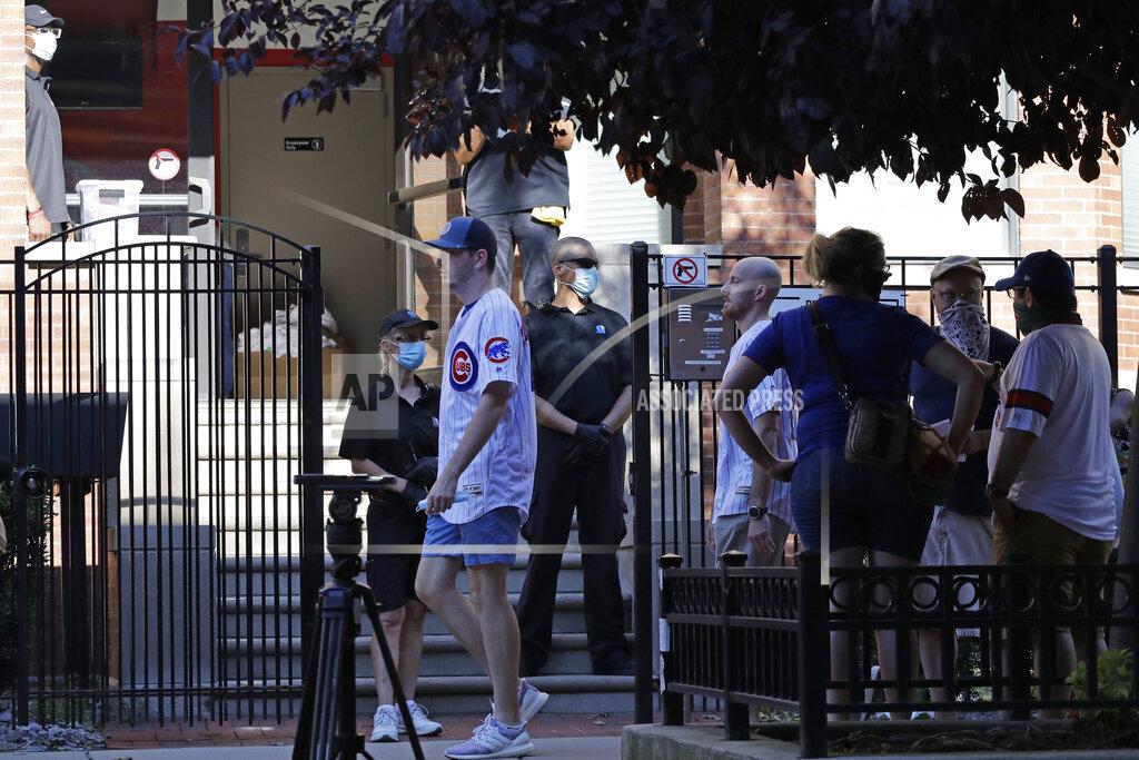 Nam Y. Huh Security guards watch fans outside a Wrigley Rooftop before an opening day baseball game between the Chicago Cubs and the Milwaukee Brewers in Chicago, Friday, July 24, 2020, in Chicago. For fans looking to see major league baseball live during the coronavirus pandemic, there are few options besides the rooftops along Waveland and Sheffield Avenues. (AP Photo/Nam Y. Huh)