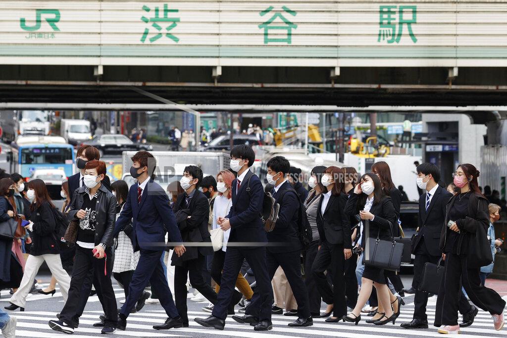 Uncredited People wearing face masks cross an intersection in the downtown in Tokyo, Japan, Thursday, April 8, 2021. Tokyo, the capital of Japan, has asked the central government for permission to implement emergency measures to curb a surge in a rapidly spreading and more contagious coronavirus variant, just over three months before the start of the Olympics. (Kyodo News via AP)