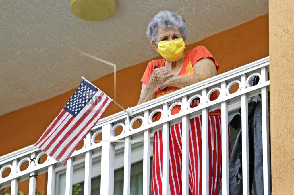 A resident from Daisy & Rosa Gardens housing buildings looks from her balcony before the City of Hialeah distribute of protective mask to the senior citizen residents as the Novel Coronavirus pandemic continues on Thursday, April 16, 2020 in Hialeah. The City of Hialeah will be distributing over 3,000 3-Ply Face Masks to Senior Housing.(David Santiago/Miami Herald via AP)