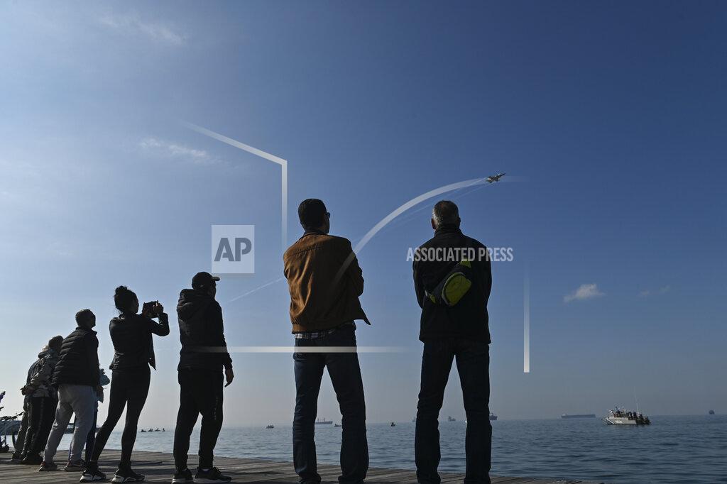 Giannis Papanikos People watch a Hellenic Air Force F-16 taking part at the annual military parade at the northern port city of Thessaloniki, Greece, on Thursday, Oct. 28, 2021 .The parade is held to celebrate Greece's refusal to align itself with a belligerent fascist Italy in 1940 and instead fight a much stronger opponent, a decision which dragged it into World War II and eventually led to a brutal occupation by Nazi Germany. (AP Photo/Giannis Papanikos)