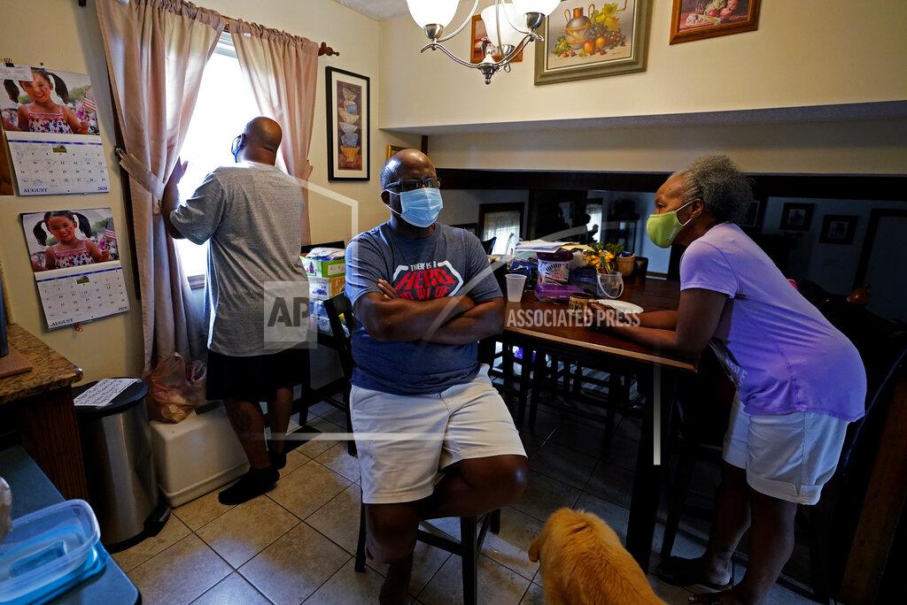 Darron Cummings Larry Brown, left, talks with his parents John and Marilyn Brown as Larry cooks dinner, Thursday, Aug. 27, 2020, in Indianapolis. Larry doesn’t know why his father’s case was comparatively mild, as John Brown spent seven days on a ventilator _ about 40 less than his son. Marilyn ended up with a mild case. (AP Photo/Darron Cummings)