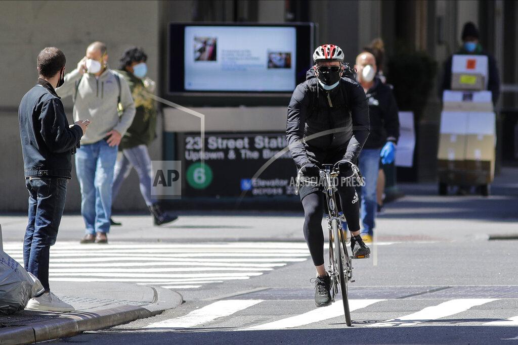 A cyclist and pedestrians wear protective masks as they cross 23rd Street, Tuesday, May 12, 2020, in New York. (AP Photo/Frank Franklin II)