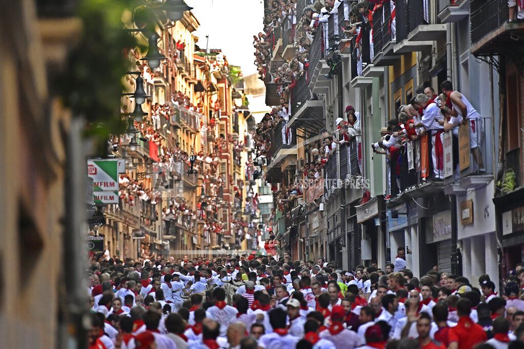 Alvaro Barrientos People run through the streets ahead of fighting bulls and steers during the first day of the running of the bulls at the San Fermin Festival in Pamplona, northern Spain, Thursday, July 7, 2022. Revelers from around the world flock to Pamplona every year for nine days of uninterrupted partying in Pamplona's famed running of the bulls festival which was suspended for the past two years because of the coronavirus pandemic. (AP Photo/Alvaro Barrientos)
