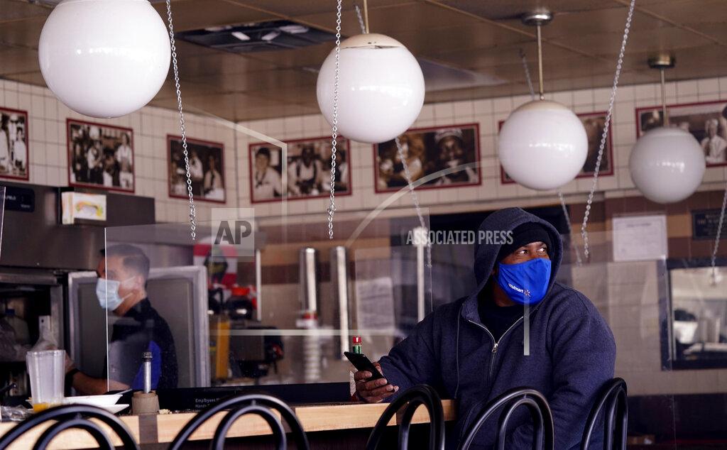 Lm Otero FILE - In this Feb. 16, 2021, file photo, Scotty Davis, right, waits for his to-go order in a dark restaurant during a cold weather blackout in Richardson, Texas. Texas on Tuesday, March 2, 2021, became the biggest state to lift its mask rule, joining a growing movement by governors and other leaders across the U.S. to loosen COVID-19 restrictions despite pleas from health officials not to let down their guard yet. (AP Photo/LM Otero, File)