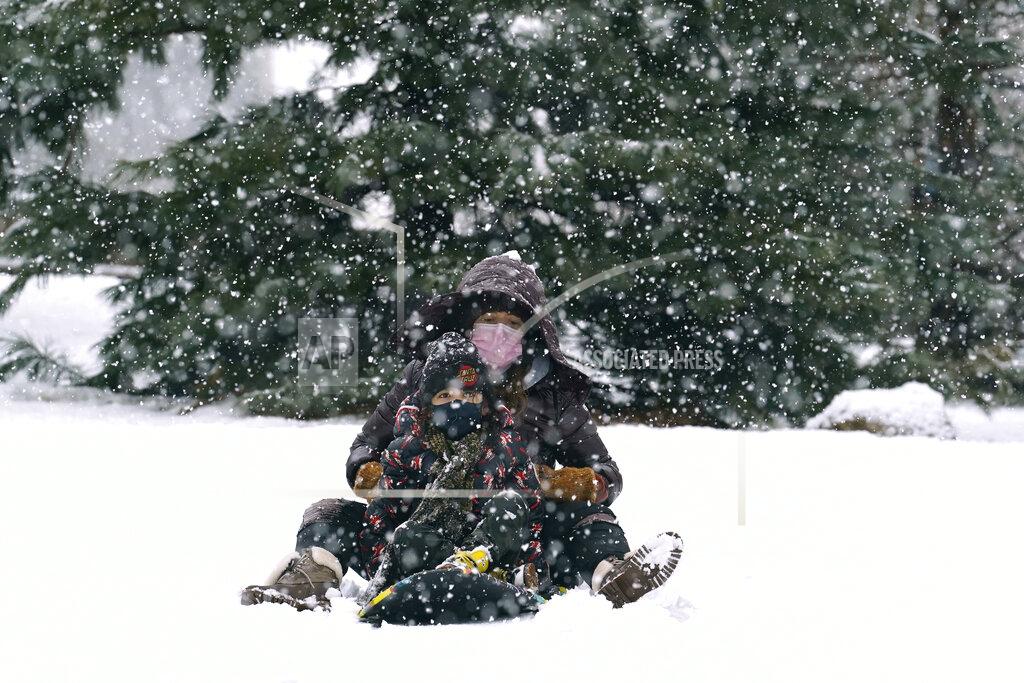 Kathy Willens A woman and child ride a snowboard down a small hill in downtown Brooklyn during a snowstorm, Sunday, Feb. 7, 2021, in New York. It was the second snowstorm to hit the New York area in less than a week. (AP Photo/Kathy Willens)