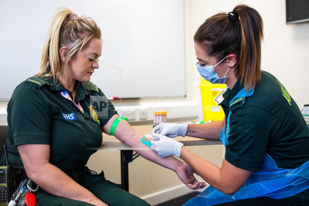 Simon Dawson Jess Baddams, a paramedic, right, takes a blood sample from Emily Humpriss, a front line ambulance worker, left, during an antibody testing program at the Hollymore Ambulance Hub, in Birmingham, England, on Friday, June 5, 2020. Making antibody tests widely available may help Britain lift its lockdown restrictions, because they show who has already had the COVID-19 and might have a degree of immunity from coronavirus. (Simon Dawson/Pool via AP)