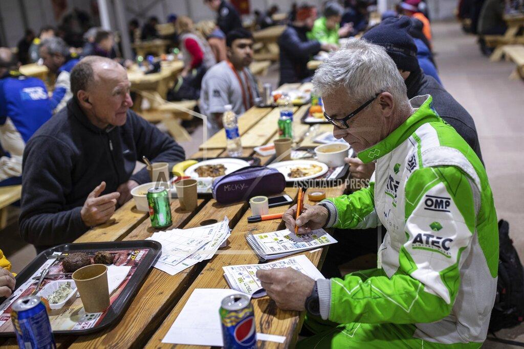 Bernat Armangue In this Sunday, Jan. 12, 2020 photo, co-driver Maurizio Dominella of Italy, checks the road book for the next stage at the restaurant of the Dakar Rally in Wadi Al Dawasir, Saudi Arabia. Formerly known as the Paris-Dakar Rally, the race was created by Thierry Sabine after he got lost in the Libyan desert in 1977. Until 2008, the rallies raced across Africa, but threats in Mauritania led organizers to cancel that year's event and move it to South America. It has now shifted to Saudi Arabia. The race started on Jan. 5 with 560 drivers and co-drivers, some on motorbikes, others in cars or in trucks. Only 41 are taking part in the Original category. (AP Photo/Bernat Armangue)