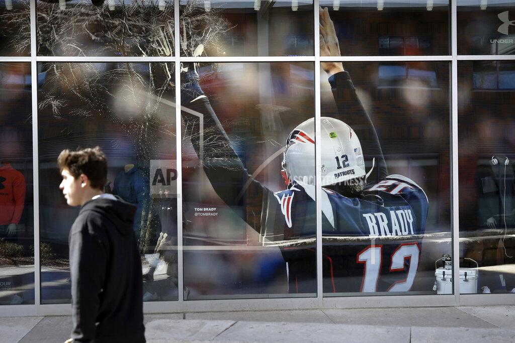 Steven Senne A passer-by walks past an oversized photograph of former New England Patriots football quarterback Tom Brady, Wednesday, March 18, 2020, at Patriot Place mall, in Foxborough, Mass. Brady said on social media on Tuesday, March 17, 2020 that he would not be returning to the Patriots and has become a free agent. (AP Photo/Steven Senne)