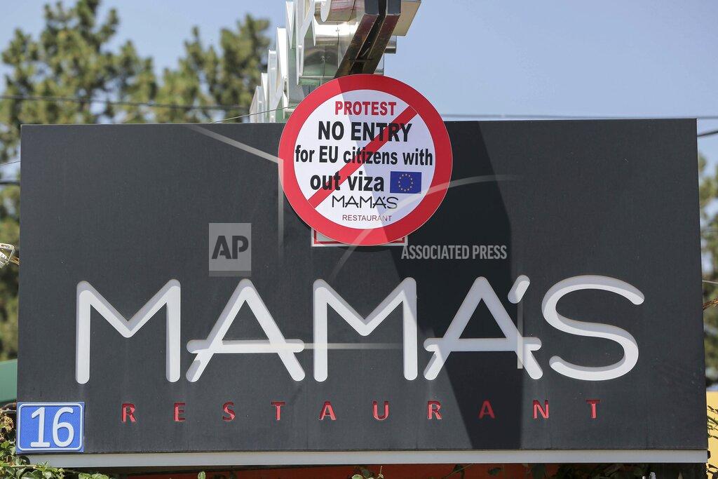 Visar Kryeziu Shpetim Pevqeli owner of the restaurant Mama's decided to put up a sign reading: "Protest, No Entry, for EU citizens without visa," in Kosovo's capital Pristina, Tuesday, June 28, 2022. The European Union’s delay in allowing visa-free travel for the people of Kosovo has spread dismay and resentment in the continent’s newest state, and one Pristina businessman has retaliated by hitting EU officials where it hurts — the stomach. (AP Photo/Visar Kryeziu)