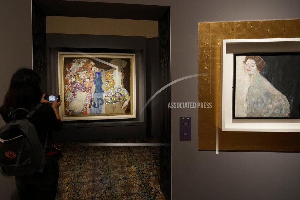 Andrew Medichini A woman admires Gustav Klimt's oil on canvas paintings "The Bride" (1918), left, and "Portrait of a Lady in White" (1917/18) on display at the exhibition "Klimt. The Secession and Italy" at the Museum of Rome, in Palazzo Braschi, Rome, during a press preview, Tuesday, Oct. 26, 2021. The exhibition, that explores Klimt's period in Italy, will be open to visitors from Oct.27, 2021 to March 27, 2022. (AP Photo/Andrew Medichini)