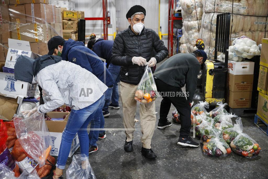 John Minchillo Fabian Arias, a Lutheran pastor with Saint Peter's Church in Manhattan, center, coordinates with volunteers as they prepare to load food delivery donations into vehicles at a produce wholesaler, Friday, May 8, 2020, in the Bronx borough of New York. (AP Photo/John Minchillo)