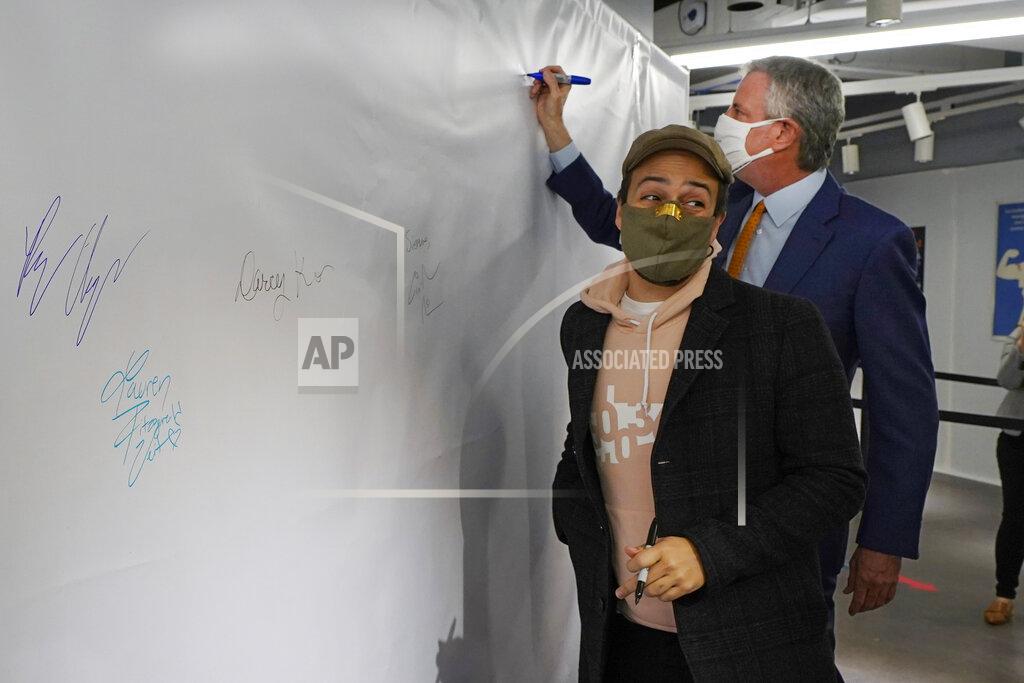 Richard Drew Actor Lin-Manuel Miranda, left, and New York Mayor Bill de Blasio, sign the autograph wall after they toured the grand opening of a Broadway COVID-19 vaccination site intended to jump-start the city's entertainment industry, in New York, Monday, April 12, 2021. (AP Photo/Richard Drew, Pool)