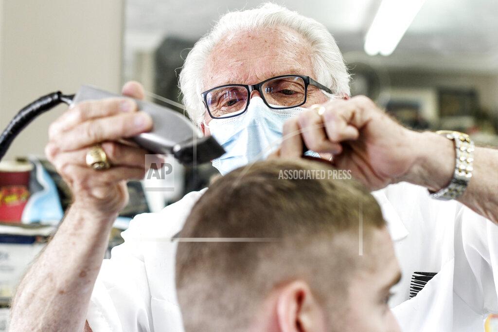 FILE - In this May 6, 2020 file photo, Karl Manke cuts hair in Owosso, Mich. The Michigan barber who defied Gov. Gretchen Whitmer and reopened his shop last spring during the coronavirus pandemic was fined $9,000 for violating licensing rules. (AP Photo /Lansing State Journal via AP)