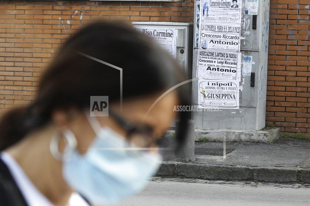 Gregorio Borgia A woman walks past obituaries posted outside the San Giuliano hospital in Giugliano in the outskirts of Naples, Italy, Saturday, Nov. 14, 2020. The pandemic has heightened the urgency of the plight of those seeking medical care in public hospitals in Italy’s economically under-developed south. (AP Photo/Gregorio Borgia)